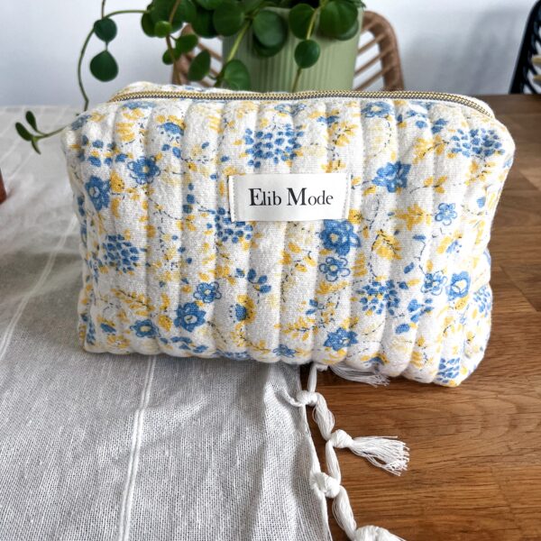 Trousse de toilette upcyclée avec motifs floraux jaunes et bleus et doublure jaune teintée au curcuma.